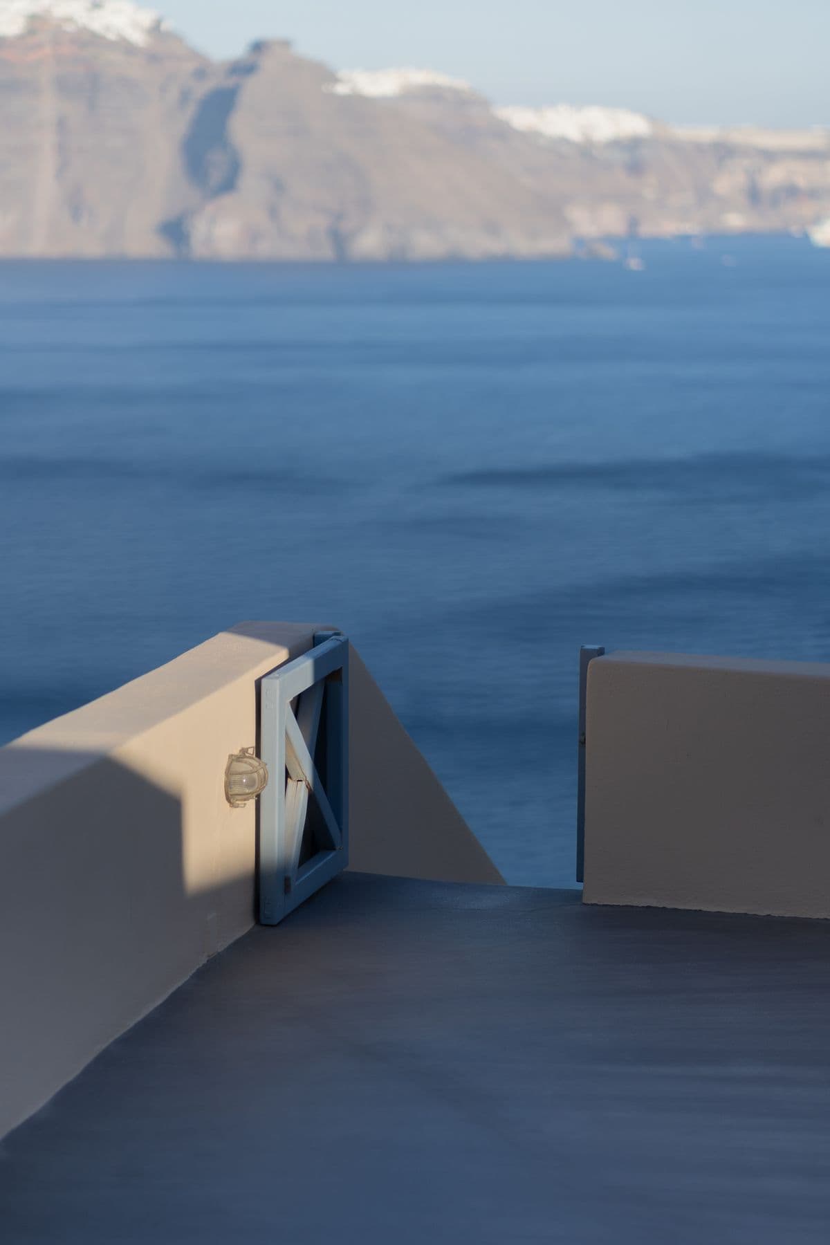An open gate overlooking the Aegean Sea and the cliffs of Santorini